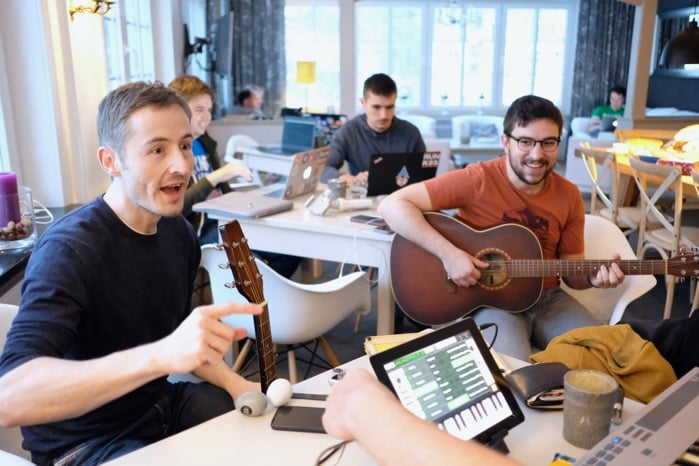 Giant Swarm team members playing guitar and singing in office